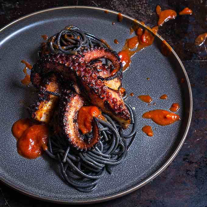 Grilled octopus over squid ink pasta
